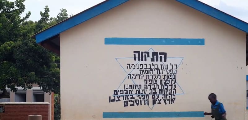 The words of Hatikvah, painted in the shape of a Star of David on a school wall at Hadassah, as a child runs past.